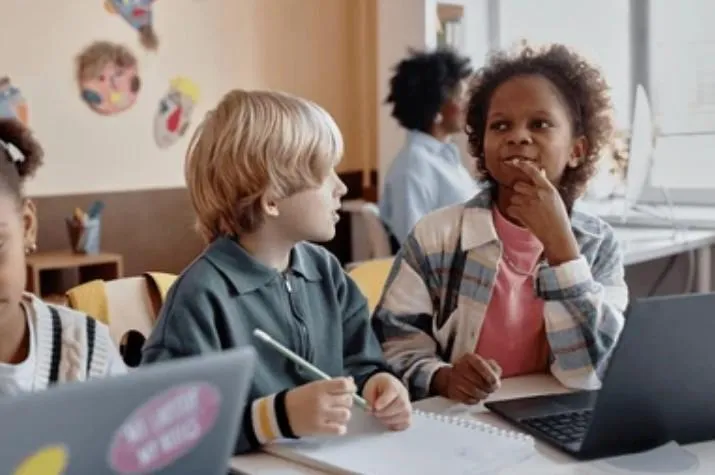 A young child and child sitting at a table with a computer
AI-generated content may be incorrect.